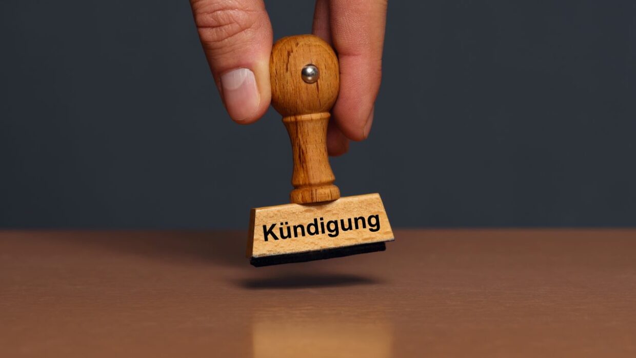 Holzstempel mit der Aufschrift „Kündigung“ schwebt über einem Tisch – Symbol für abfindungen betriebsbedingte kündigung.