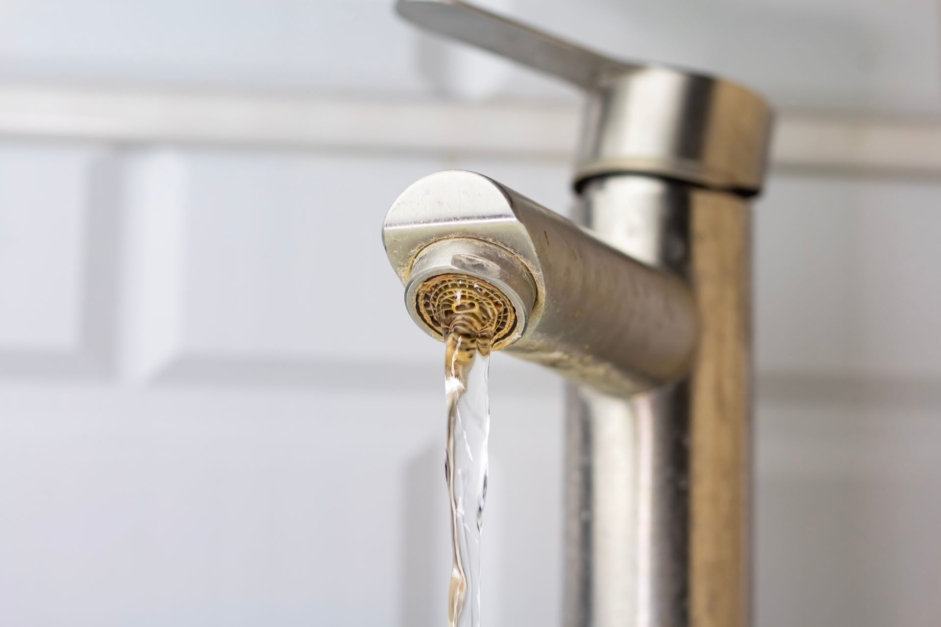 Kalkablagerungen an Küchenwasserhahn mit laufendem Wasser