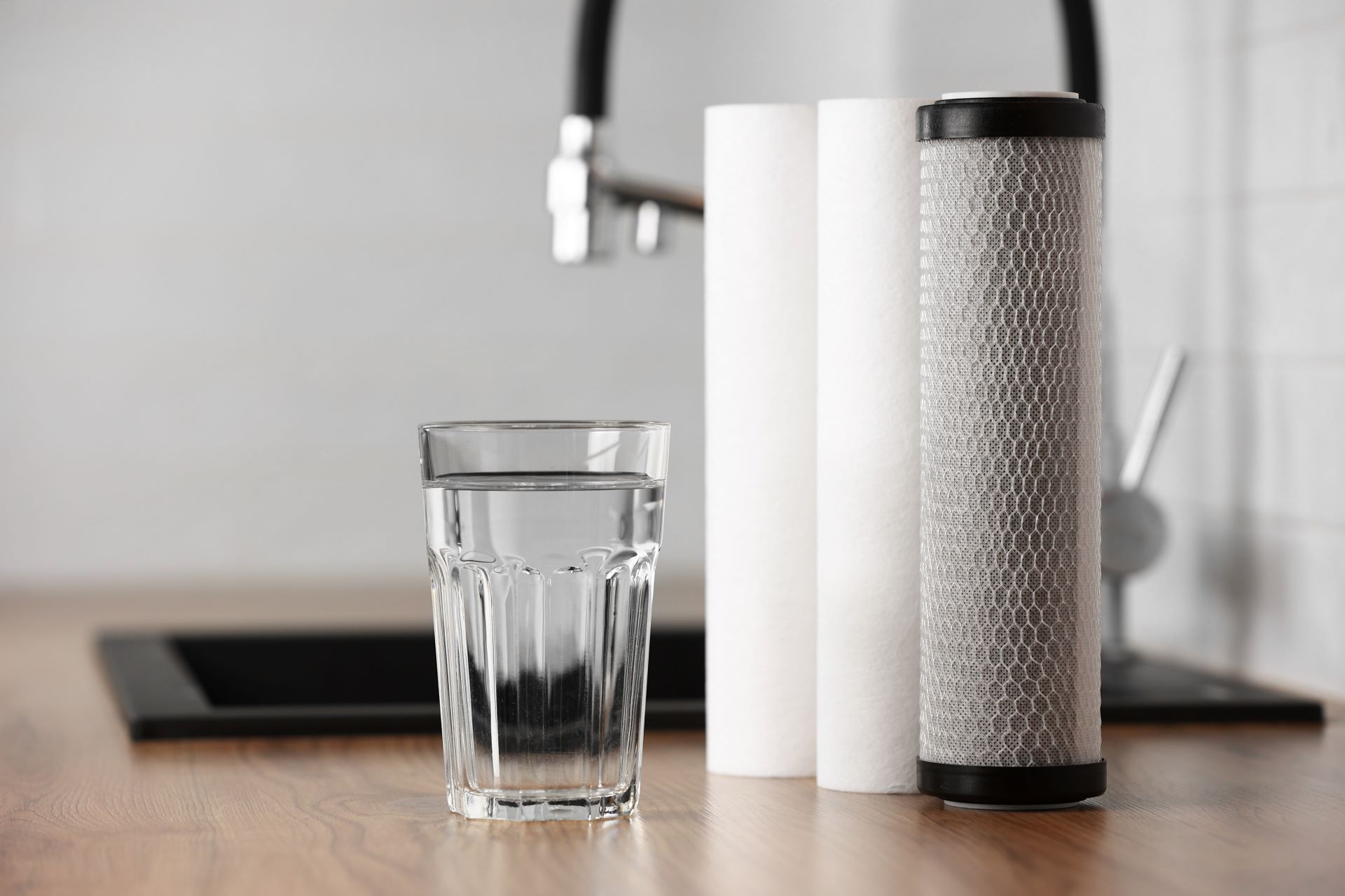 Glas Wasser neben Filterkartuschen auf Küchenarbeitsplatte