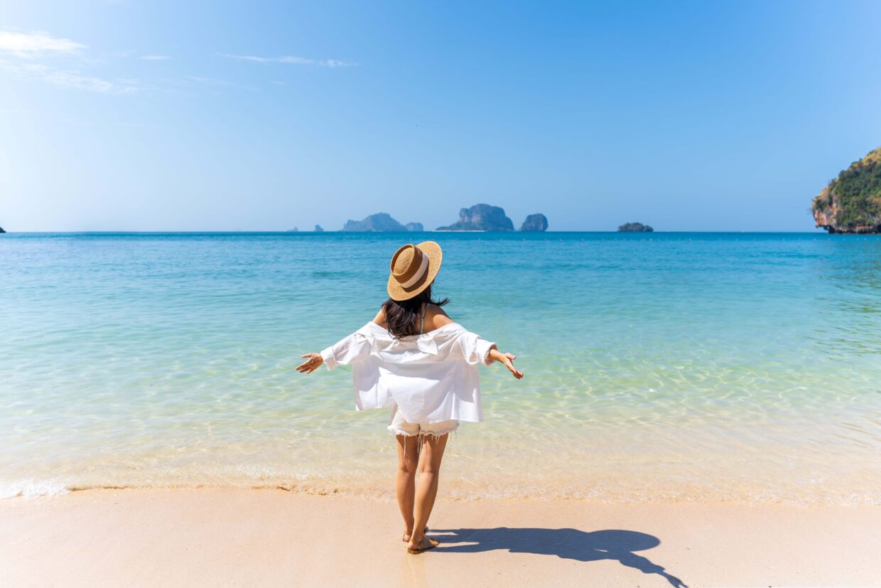Junge asiatische Frau entspannt sich und genießt einen wunderschönen weißen Sandstrand an einem sonnigen Tag, Reisen im Sommerurlaub